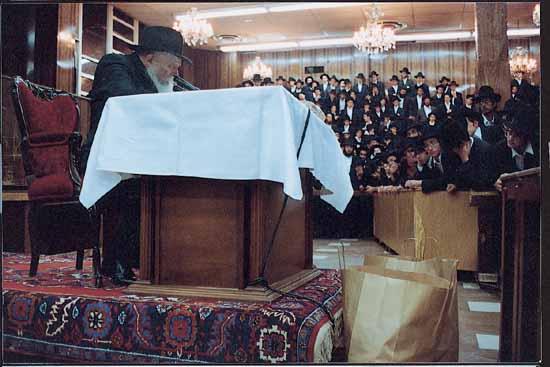 The Rebbe speaking at his lectern before a full hall